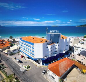 A hotel with a prominent 'HOTEL' sign, a rooftop terrace, and a view of the ocean. - Ingleses Praia Hotel (Florianópolis)