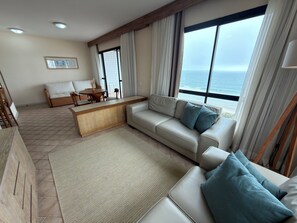 A modern living room with a sofa, a coffee table, and a view of the ocean. - Ingleses Praia Hotel (Florianópolis)