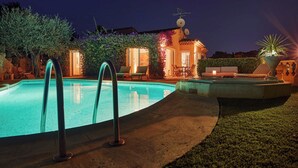 A swimming pool with a clear view of the surrounding area, including a patio with outdoor furniture and a building with a satellite dish.