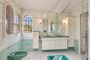 A bathroom with a large mirror, a bidet, and a shower.