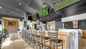 Eine Sportbar und Grill mit einer langen Theke, mehreren Fernsehbildschirmen und einer Wand mit Holzverkleidung.