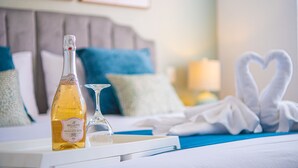 Ein Hotelzimmer mit einem Bett, einer Weinflasche, einem Glas und einem Handtuch, die zu einem Herz geformt sind.