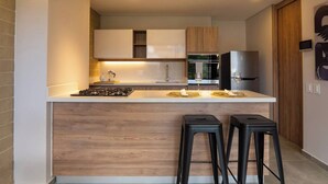 Una cocina moderna con una isla central, electrodomésticos de acero inoxidable y armarios de madera.