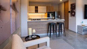 A modern kitchen with a central island, bar stools, and a dining area with a table and chairs. - Comfort and style in Medellin 301 (Medellín)