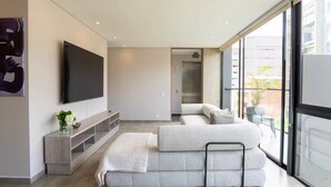 A modern living room with a large flat-screen TV, a sofa, and a glass door leading to an outdoor area. - Perfect home in Medellín 501 (Medellín)