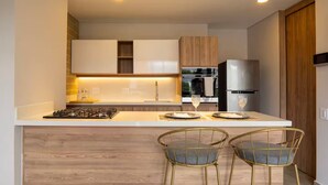 A modern kitchen with a central island, stainless steel appliances, and a wooden backsplash. - Perfect home in Medellín 501 (Medellín)
