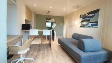 A modern living room with a sofa, a dining table with chairs, and a TV.
