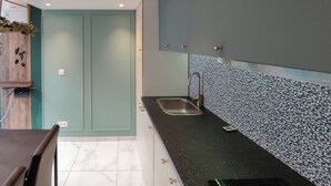 A modern kitchen with a dark countertop, a sink, and a backsplash with a pebble pattern.