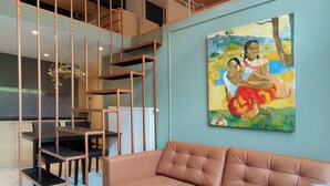 A modern living room with a sofa, dining area, and artwork on the wall.
