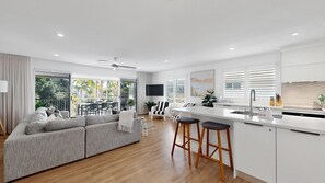 Una cocina moderna con una isla central, piso de madera y una zona de comedor con sofá y sillas.