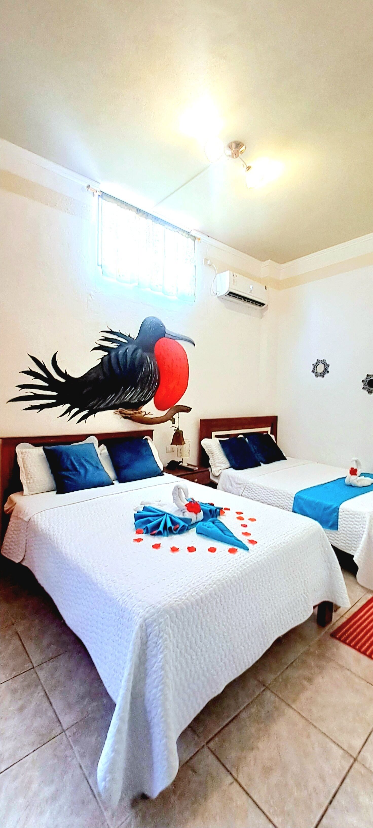 A hotel room with two beds, white bedding, a red balloon, and a swan decoration.