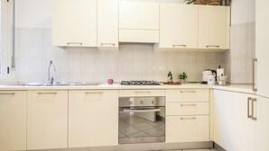 Eine moderne Küche mit weißen Schränken, einem eingebauten Backofen und einer Spüle aus Edelstahl.