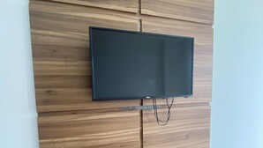Litteänäyttöinen televisio on kiinnitetty puiseen seinään, ja sen takaa kulkee kaapeli seinän keskeltä alaspäin.