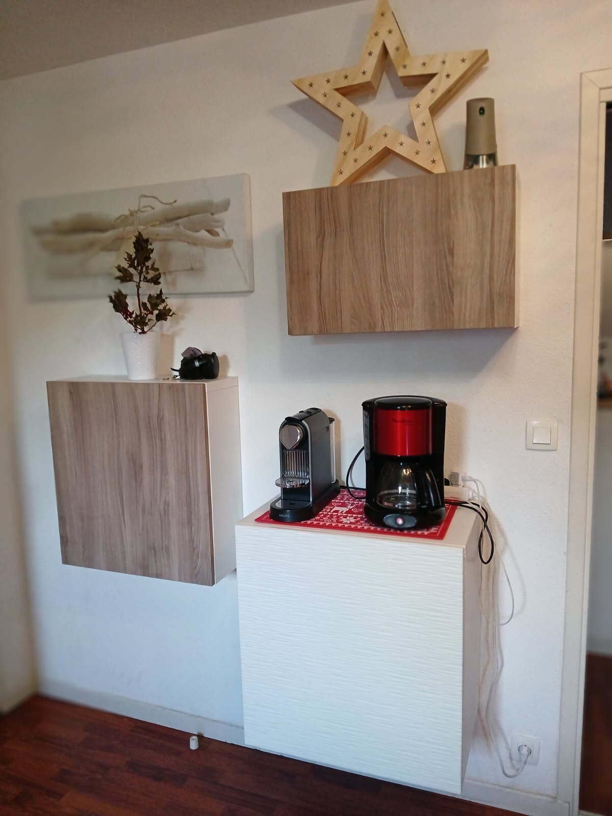 A modern kitchen with a coffee maker, a decorative star, and a potted plant on a cabinet.