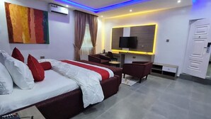 Quarto de hotel moderno com uma cama grande, uma escrivaninha, uma televisão e um guarda-roupa.