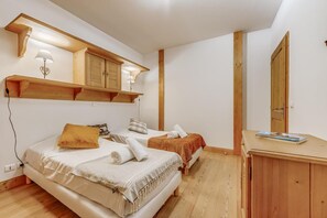A bedroom with two beds, wooden headboards, a small desk, and a mirror.