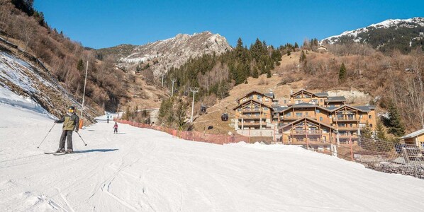 A ski resort with wooden lodges, a ski slope, and a mountain backdrop.