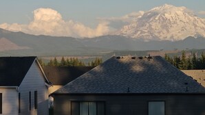 Una casa con techo inclinado, chimenea visible y una montaña al fondo.