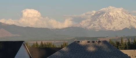 Una casa con techo inclinado, chimenea visible y una montaña al fondo.