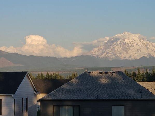 A house with a sloped roof, a visible chimney, and a mountain in the background.