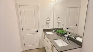 Un baño moderno con dos lavamanos, un espejo grande y un inodoro.
