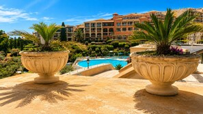 A pool area with two large planters, a clear blue pool, and a building with multiple balconies in the background.