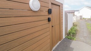 Un mur en bois avec une porte, une boîte aux lettres et un panneau indiquant un point de vue sur l’église Saint-André.