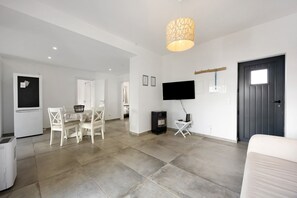A modern living room with a dining area, a flat-screen TV, and a dark door. - Villa Vista Azul - Praia Da Luz (Luz)