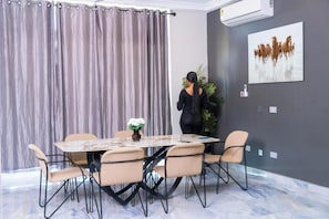 Un salón de conferencias con una mesa de mármol, sillas color beige, una planta en maceta y un cuadro de caballos en la pared.