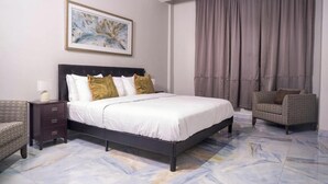 Une chambre d’hôtel avec un grand lit, une table de chevet, une chaise et un tableau au mur.