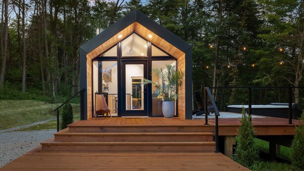 A modern cabin with a wooden deck, large windows, and a staircase leading to the entrance. - Modern+Hot Tub+Hocking Hills+ Near Waterfalls (Logan)