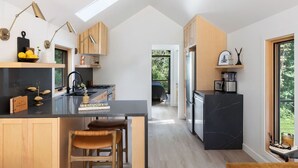 A modern kitchen with a central island, wooden cabinets, and a black marble countertop. - Modern+Hot Tub+Hocking Hills+ Near Waterfalls (Logan)
