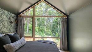 A bedroom with a large window, a bed, and a patterned wall. - Modern+Hot Tub+Hocking Hills+ Near Waterfalls (Logan)