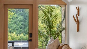 A modern living room with a large sliding glass door leading to an outdoor terrace. - Modern+Hocking Hills+Hot Tub+Near Waterfalls (Logan)