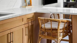A modern kitchen with marble countertops, wooden cabinets, a large island with chairs, and two pendant lights. - Modern+Hocking Hills+Hot Tub+Near Waterfalls (Logan)