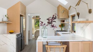 A modern kitchen with a marble countertop, wooden cabinets, and a skylight. - Modern+Hocking Hills+Hot Tub+Near Waterfalls (Logan)