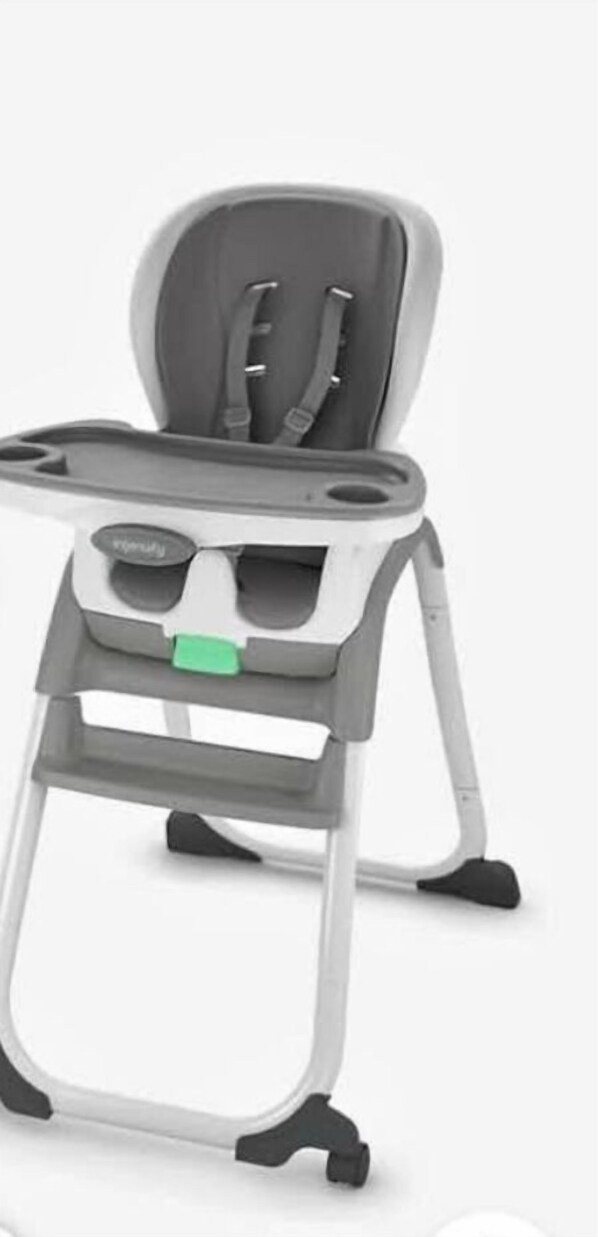 Una trona con mesita y un cojín de asiento verde.