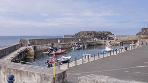 A harbor with boats docked, a concrete pier, and a rocky outcrop in the background. - 41 Church View (Portstewart)