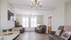A spacious living room with a large window, a chandelier, a sofa, and a dining area. - 41 Church View (Portstewart)