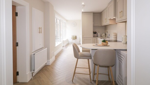 A modern kitchen with a central island, wooden flooring, and light-colored cabinetry. - 41 Church View (Portstewart)