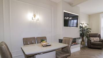 A dining area with a table, chairs, a remote control, and a small plant on the table.