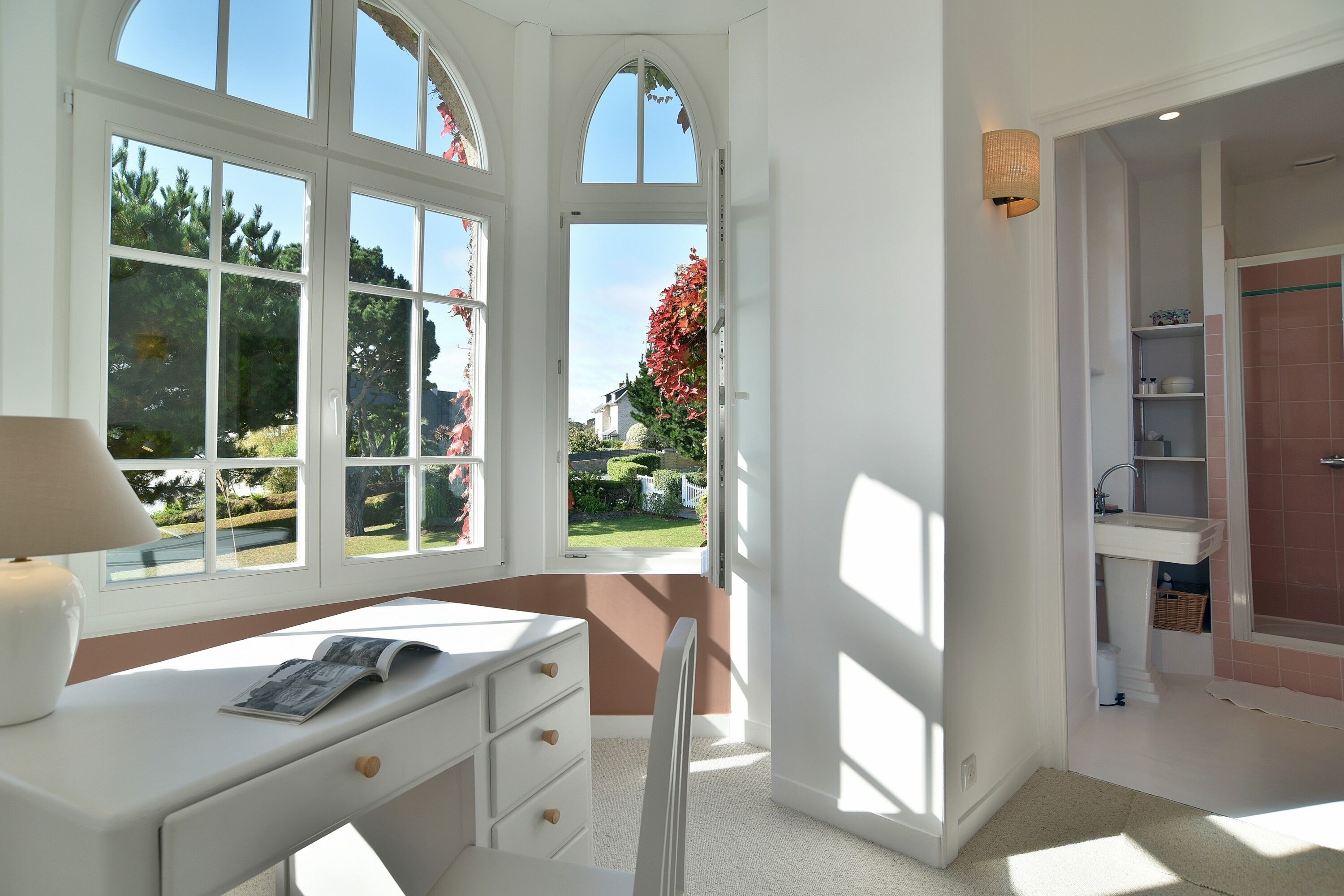 A bright room with a desk, a chair, and a window overlooking a garden.