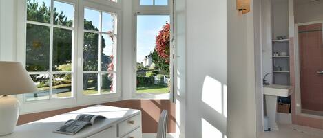 A bright room with a desk, a chair, and a window overlooking a garden.