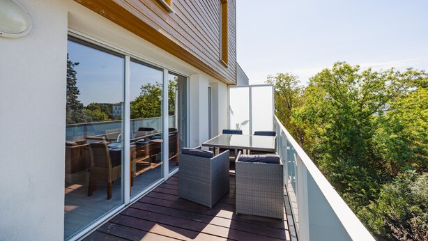 A modern balcony with glass doors, wicker furniture, and a view of trees. - An Ti Gwerned - Proche Aéroport Rennes (Saint-Jacques-de-la-Lande)