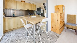 A compact kitchen with wooden cabinets, a stainless steel sink, and a dining area with a table and chairs. - An Ti Gwerned - Proche Aéroport Rennes (Saint-Jacques-de-la-Lande)