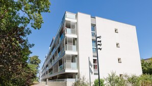 A modern multi-story building with balconies, a clear sky, and surrounding greenery. - An Ti Gwerned - Proche Aéroport Rennes (Saint-Jacques-de-la-Lande)