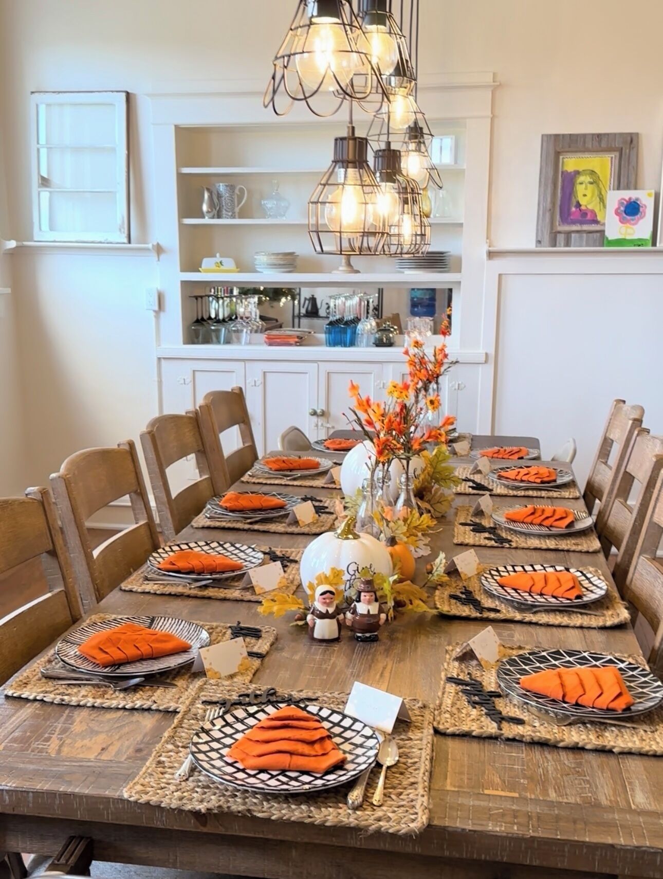 A dining table set for a meal with placemats, plates, and a centerpiece.