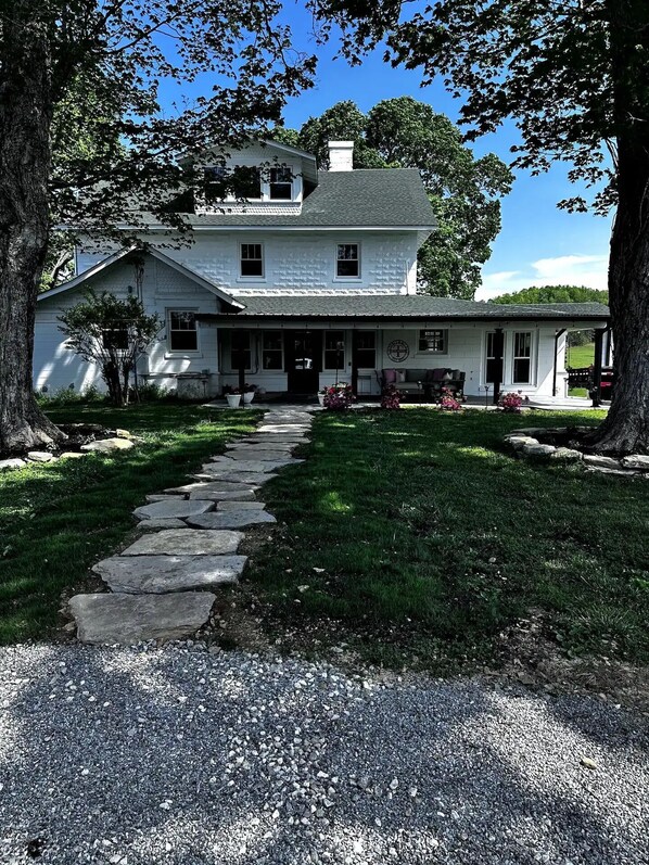 A two-story house with a stone pathway leading to the front door.