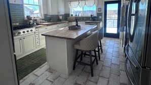 A kitchen with a central island, a chandelier, and a large refrigerator. - Charming Farmhouse, Peaceful and Private (Hurricane Mills)