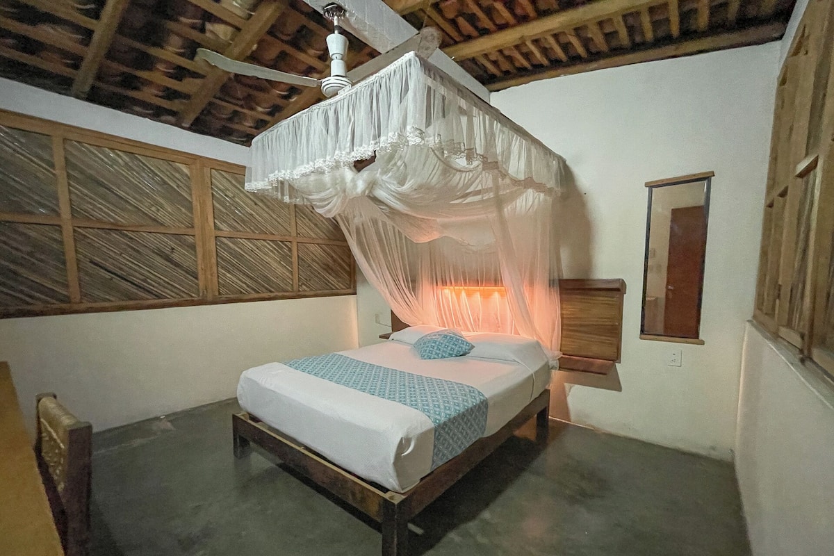 Un lit à baldaquin, une tête de lit en bois et une table de chevet avec une lampe.